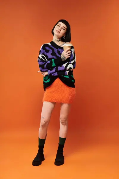 A young woman with vibrant tattoos and short hair stands proudly in a colorful sweater, exuding confidence. — Stock Photo