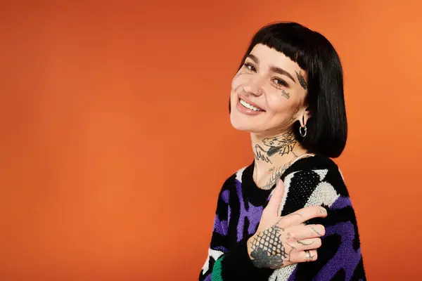 A young woman with short hair and tattoos showcases her lively personality in a bright sweater. — Stock Photo