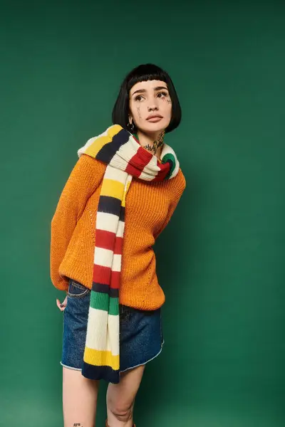 A young woman with tattoos poses in a cozy sweater, exuding warmth and confidence in a vibrant studio setting. — Stock Photo