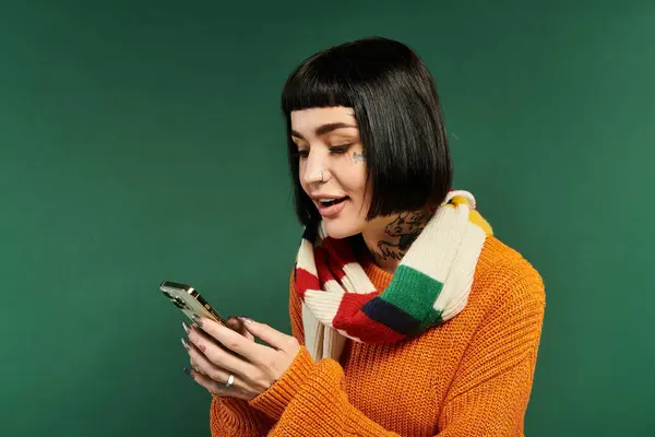 A young woman with tattoos enjoys a cozy atmosphere while checking her phone, exuding warmth and charm. — Stock Photo