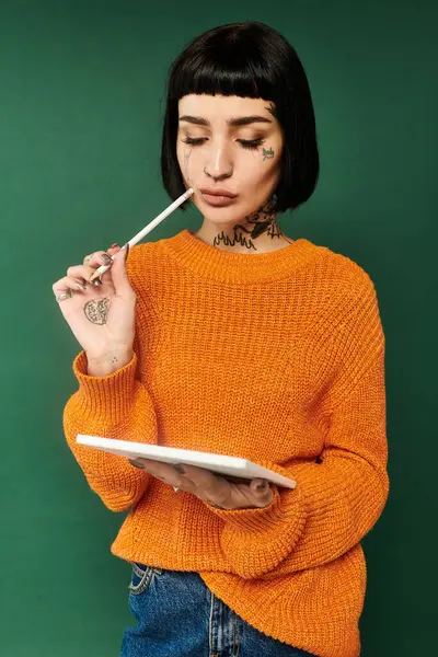 Uma jovem mulher com cabelo curto e tatuagens contempla enquanto veste uma camisola quente em um estúdio. — Fotografia de Stock