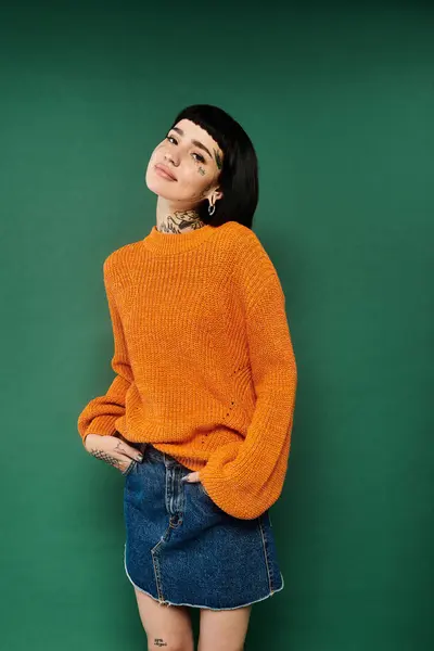 A stylish young woman with short hair and tattoos showcases her cozy sweater while posing confidently. — Stock Photo