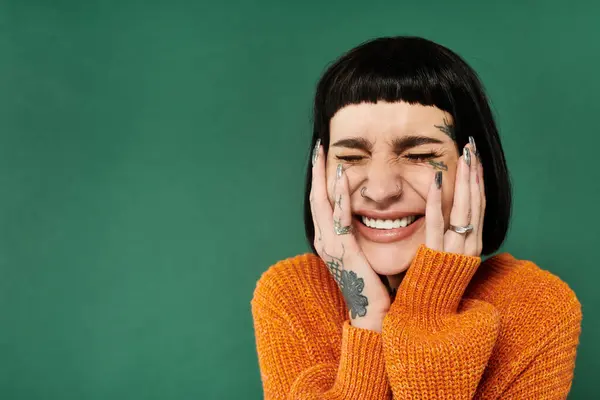 A young woman with short hair and vibrant tattoos expresses joy while wearing a cozy sweater. — Stock Photo
