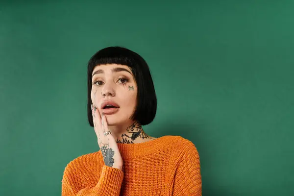 A young woman with short hair and tattoos explores a moment of introspection in a cozy sweater. — Stock Photo