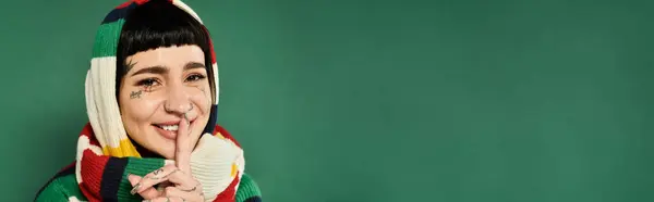 This young woman with tattoos and short hair gives a warm smile while posing in a colorful sweater and scarf — Stock Photo