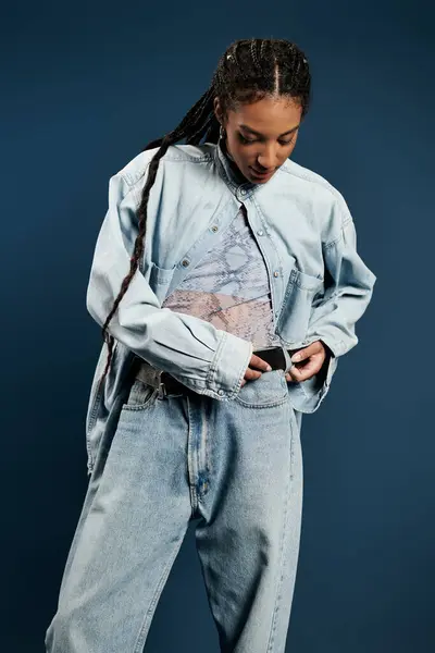 A young woman in chic denim attire adjusts her belt, exuding confidence and style. — Stock Photo