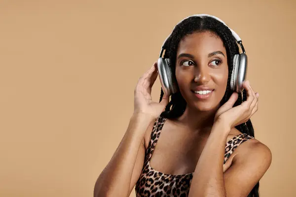A young woman showcases her trendy outfit while happily listening to music with headphones. — Stock Photo
