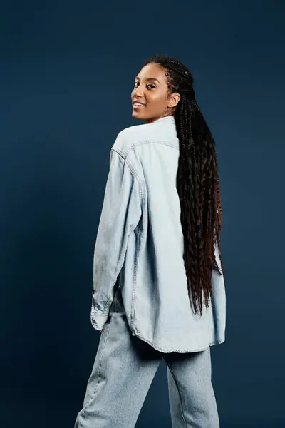 A confident young woman poses playfully in trendy denim attire, showcasing her long hair. — Stock Photo