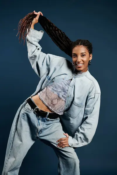 A beautiful young woman in fashionable clothing strikes a dynamic pose while holding her hair back. — Stock Photo