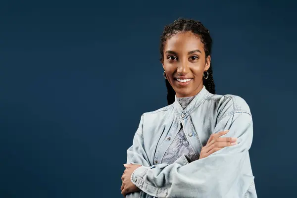 A confident young woman shows off her stylish outfit against a bright blue backdrop. — Stock Photo