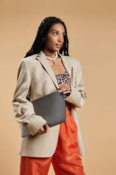 A young woman exudes confidence in trendy attire while holding a laptop, poised for adventure. — Stock Photo