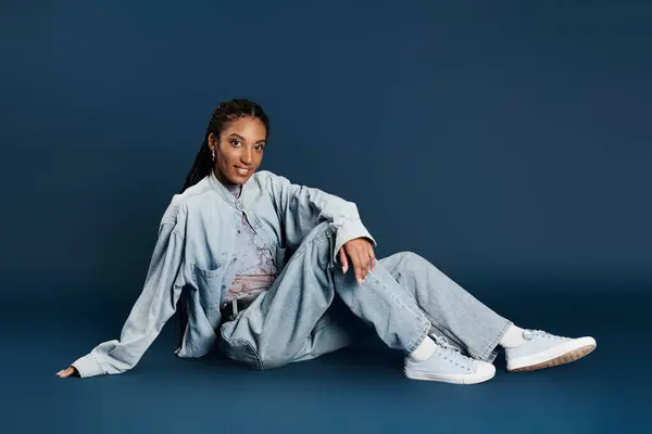 The young woman showcases her fashionable outfit while relaxing on the floor, exuding confidence. — Stock Photo