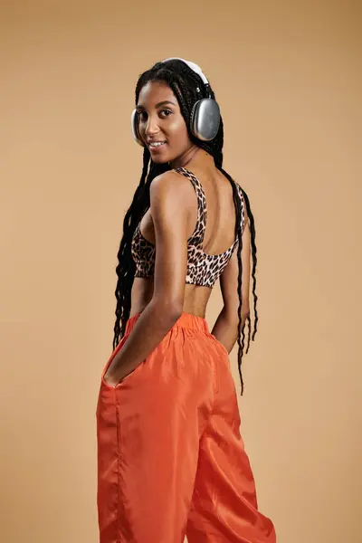 A beautiful young woman in trendy attire grooves to her favorite tunes while posing confidently. — Stock Photo