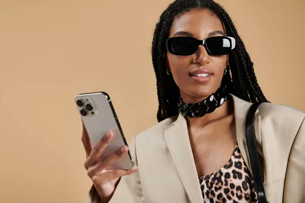 Une jeune femme élégante arbore sa tenue tendance et son smartphone, rayonnant de confiance. — Photo de stock