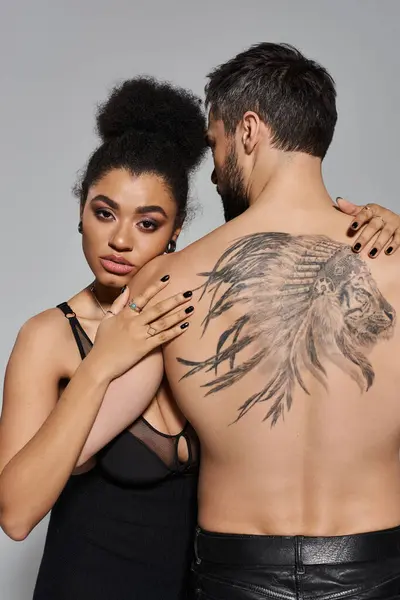 A couple shares a tender embrace, showcasing a striking tattoo on the mans back. — Stock Photo