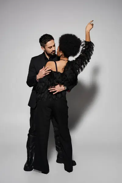 A glamorous couple enjoys a tender moment filled with warmth and affection against a soft backdrop. — Stock Photo