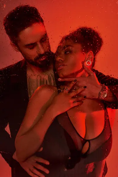 A loving couple shares an intimate moment, enveloped in warm red tones and vibrant energy. — Stock Photo