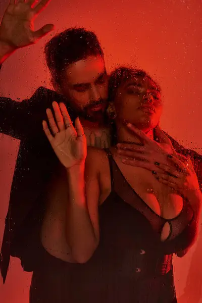 A couple shares an intimate moment, surrounded by mist and enveloped in soft red light. — Stock Photo