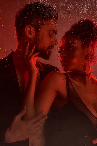 A loving couple shares an electric moment, illuminated by soft lighting and surrounded by droplets. — Stock Photo
