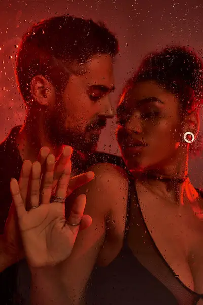 A loving couple shares an intimate moment, framed by droplets on glass in warm lighting. — Stock Photo