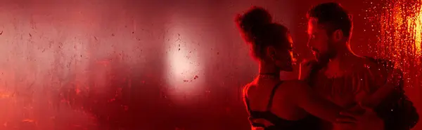 A loving couple shares an intimate moment, wrapped in each others arms, glowing in red light. — Stock Photo