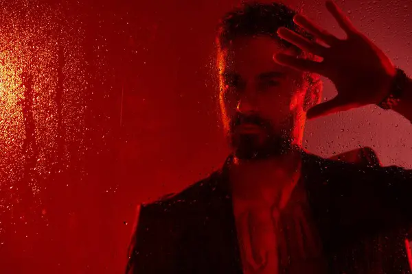 Handsome man in suit posing in red lights. — Stock Photo