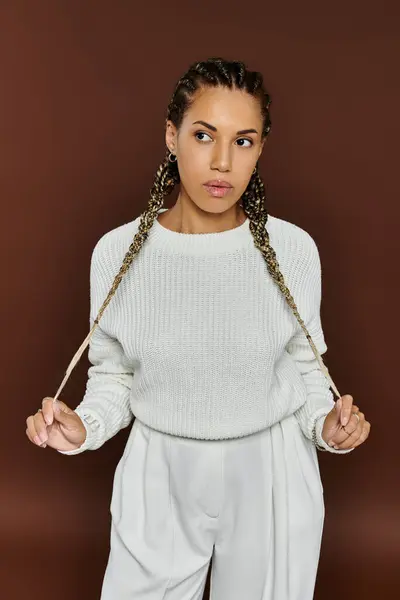 A stylish young woman stands confidently, wearing autumn inspired attire with elegant braids. — Stock Photo