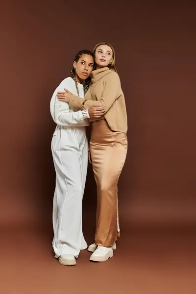 Um momento terno compartilhado entre duas jovens mulheres vestidas com roupas elegantes de outono, irradiando calor. — Fotografia de Stock