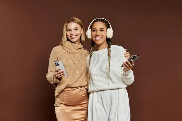 A cheerful couple in stylish autumn outfits shares a laugh while using their phones. — Stock Photo