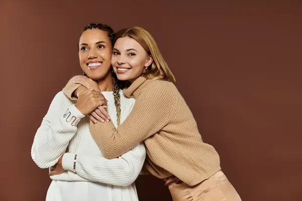 Un momento de alegría compartido entre una joven pareja vestida con trajes de otoño, sonriendo y abrazando. - foto de stock