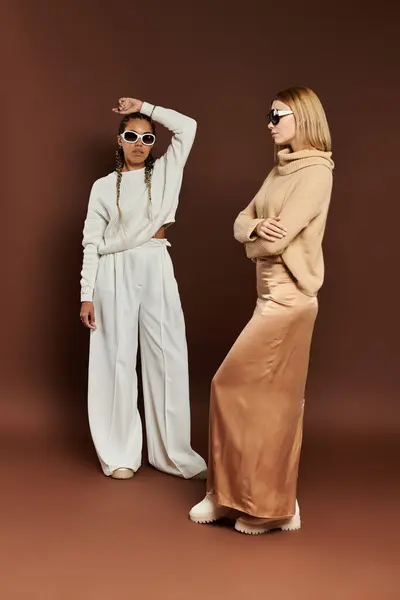 A beautiful lesbian couple showcases autumn fashion with playful poses in a warm environment. — Stock Photo
