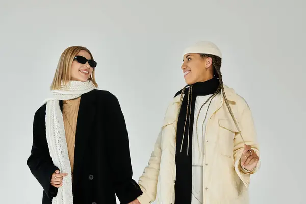 A joyful moment between two women dressed warmly for autumn, smiling and holding hands together. — Stock Photo