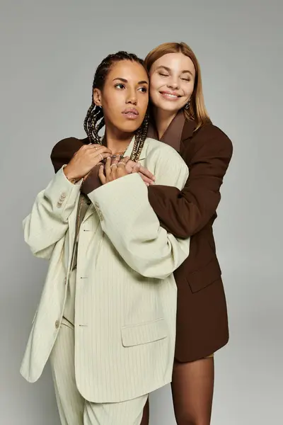Dos hermosas mujeres comparten un momento de amor mientras se visten con atuendo de otoño de moda. - foto de stock
