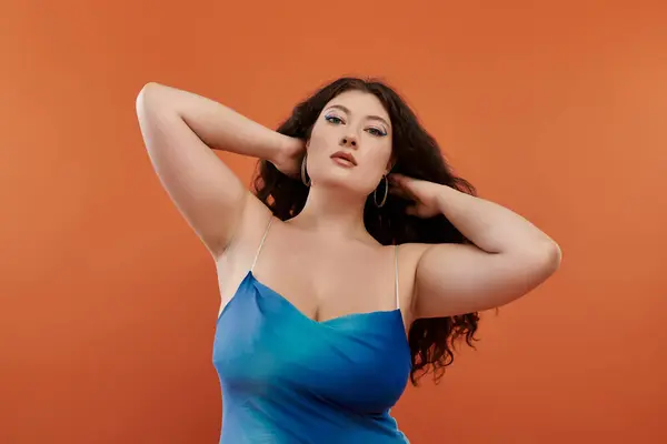 Una hermosa mujer de talla grande muestra su personalidad y estilo en un vestido azul, golpeando una pose con confianza. - foto de stock