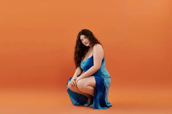 Uma jovem mulher plus-size mostra seu estilo deslumbrante e confiança em um vestido azul chique em um fundo brilhante. — Fotografia de Stock