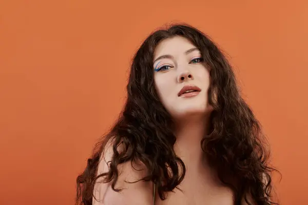 A confident plus-size woman flaunts her style against a bright orange backdrop. — Stock Photo