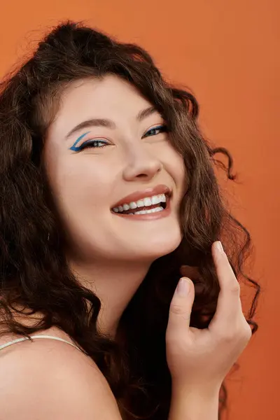 A young plus size woman shines confidently, showcasing her joyful spirit against an orange backdrop. — Stock Photo