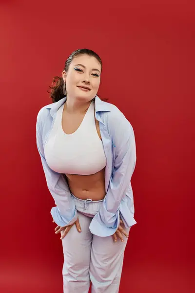 A beautiful young woman embraces her curves, showcasing colorful makeup and stylish attire in a creative studio. — Stock Photo