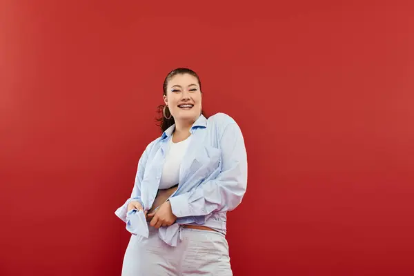 Una giovane, bella donna plus-size mette in mostra il suo trucco vibrante mentre posa con stile in un ambiente di studio. — Foto stock