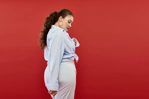 Eine atemberaubende junge Plus-Size-Frau präsentiert ihre selbstbewusste Pose und ihr farbenfrohes Make-up in einem eindrucksvollen Atelierumfeld. — Stockfoto