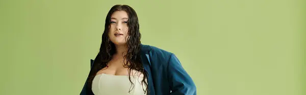 A young, beautiful plus size woman poses confidently in a suit, showcasing her unique style in a studio setting. — Stock Photo