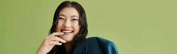 A young plus size woman with curly hair confidently poses in a suit, radiating joy in a studio setting. — Stock Photo