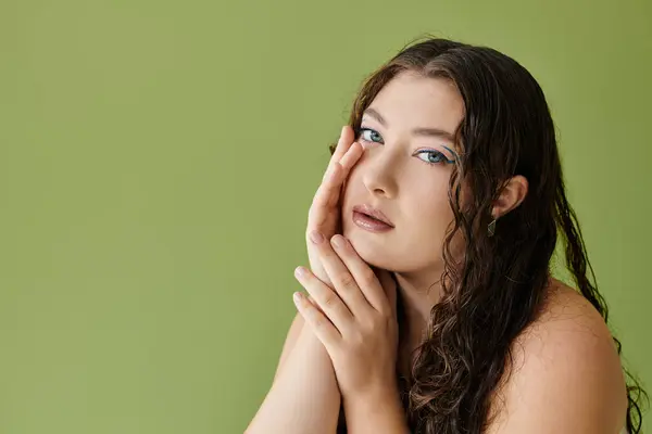 A young woman with curly hair showcases her beauty, set against a bright green background. — Stock Photo