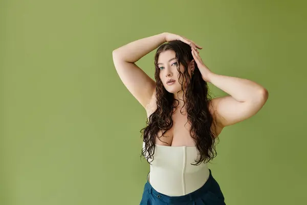 A stunning plus size model showcases her beauty in a corset while posing confidently against a green background. — Stock Photo