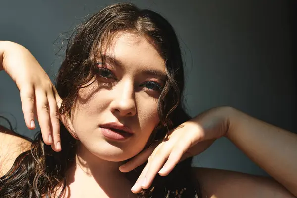 Потрясающая женщина plus-size уверенно позирует на фоне серого задника. — стоковое фото