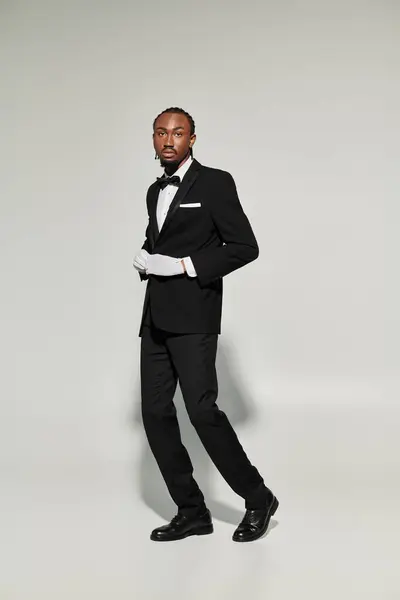 A young man dressed in a tailored suit and vest showcases elegance and poise against a neutral backdrop. — Stock Photo