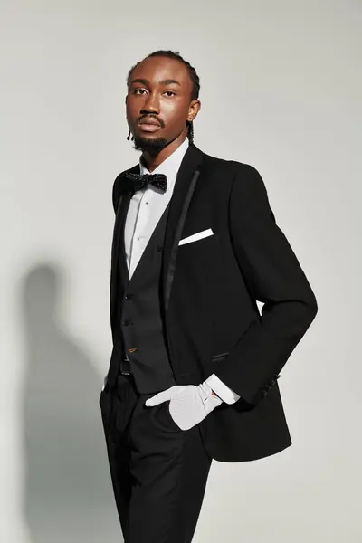 A young African American man dressed elegantly in a suit, vest, and bow tie strikes a confident pose. — Stock Photo