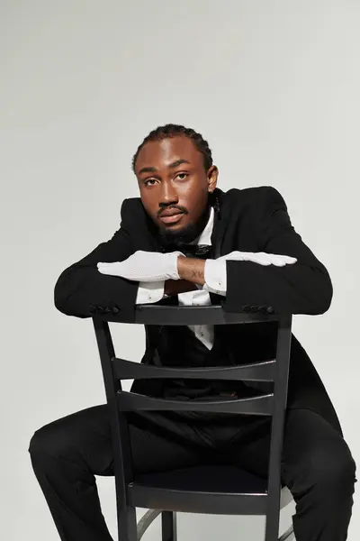 A young African American man dressed in a stylish suit and vest leans confidently on a chair, exuding sophistication. — Stock Photo