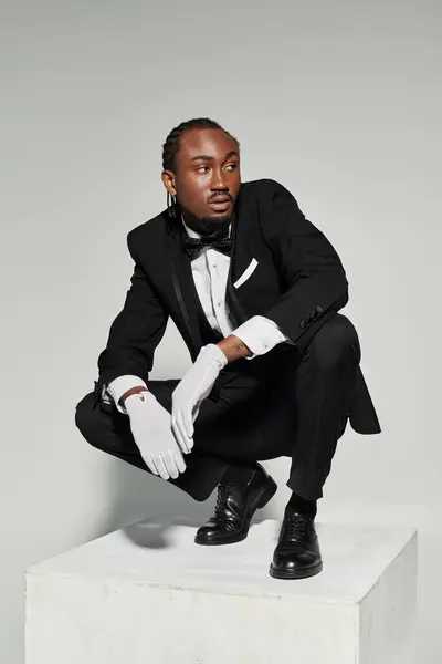 A dapper young man embraces elegance, showcasing his well-fitted suit and confident pose on a neutral background. — Stock Photo