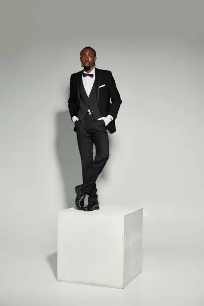 A stylish young man dressed in a suit and vest stands confidently on a pedestal, showcasing elegance. — Stock Photo